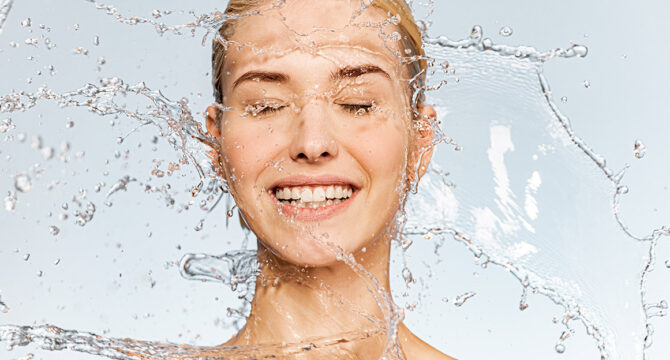 Beau visage de femme radieuse aspergée d'eau, peau, lisse, fraîche, tonique, lumineuse, éclatante de santé